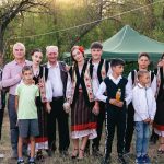 A group of people in traditional Romanian clothing standing together in a park