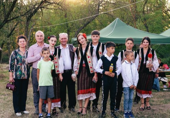 A group of people in traditional Romanian clothing standing together in a park