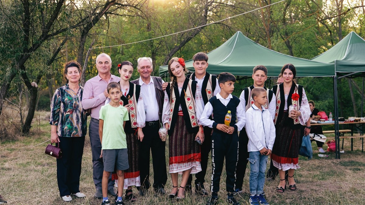 A group of people in traditional Romanian clothing standing together in a park